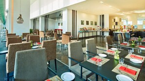 A spacious dining area with high ceilings, modern furniture, and a buffet setup.