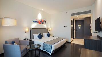 A modern hotel room with a bed, a sofa, a small table, and a TV.