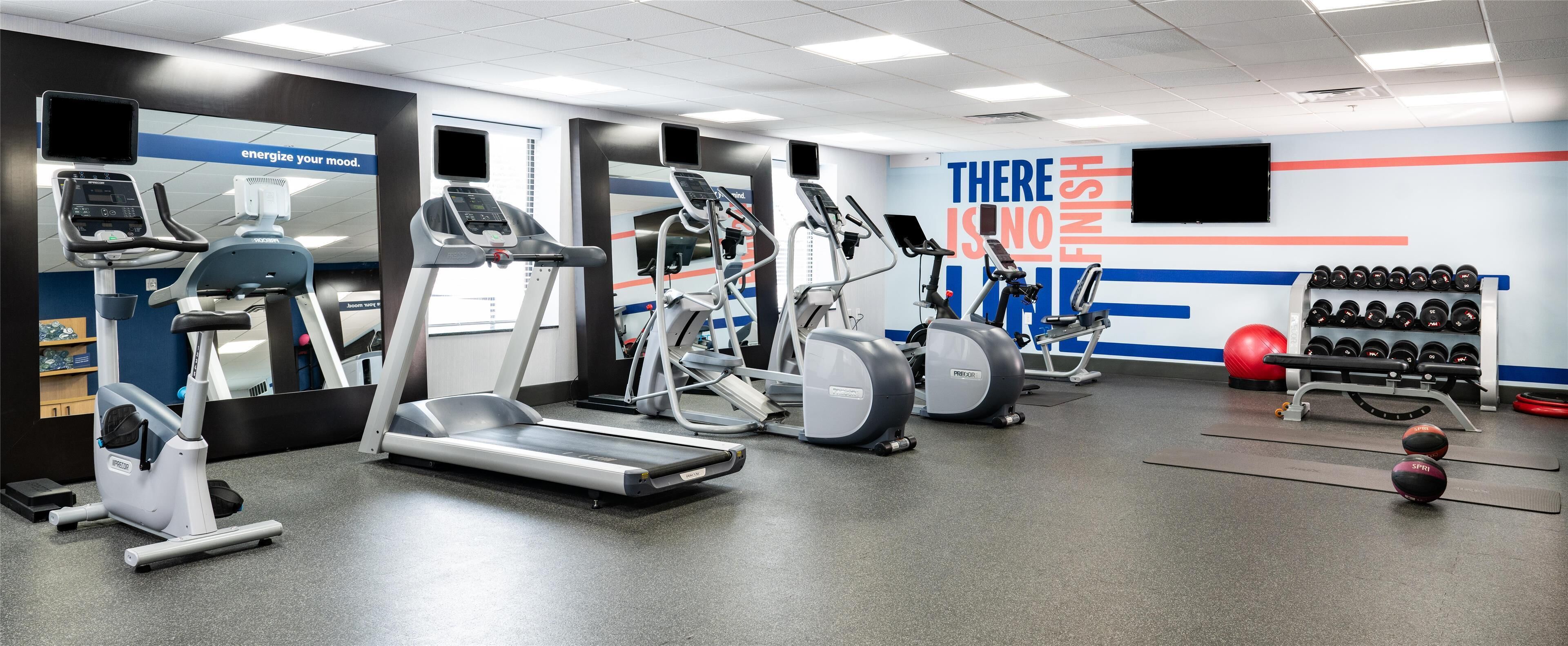 A gym with treadmills, elliptical machines, and weightlifting equipment.