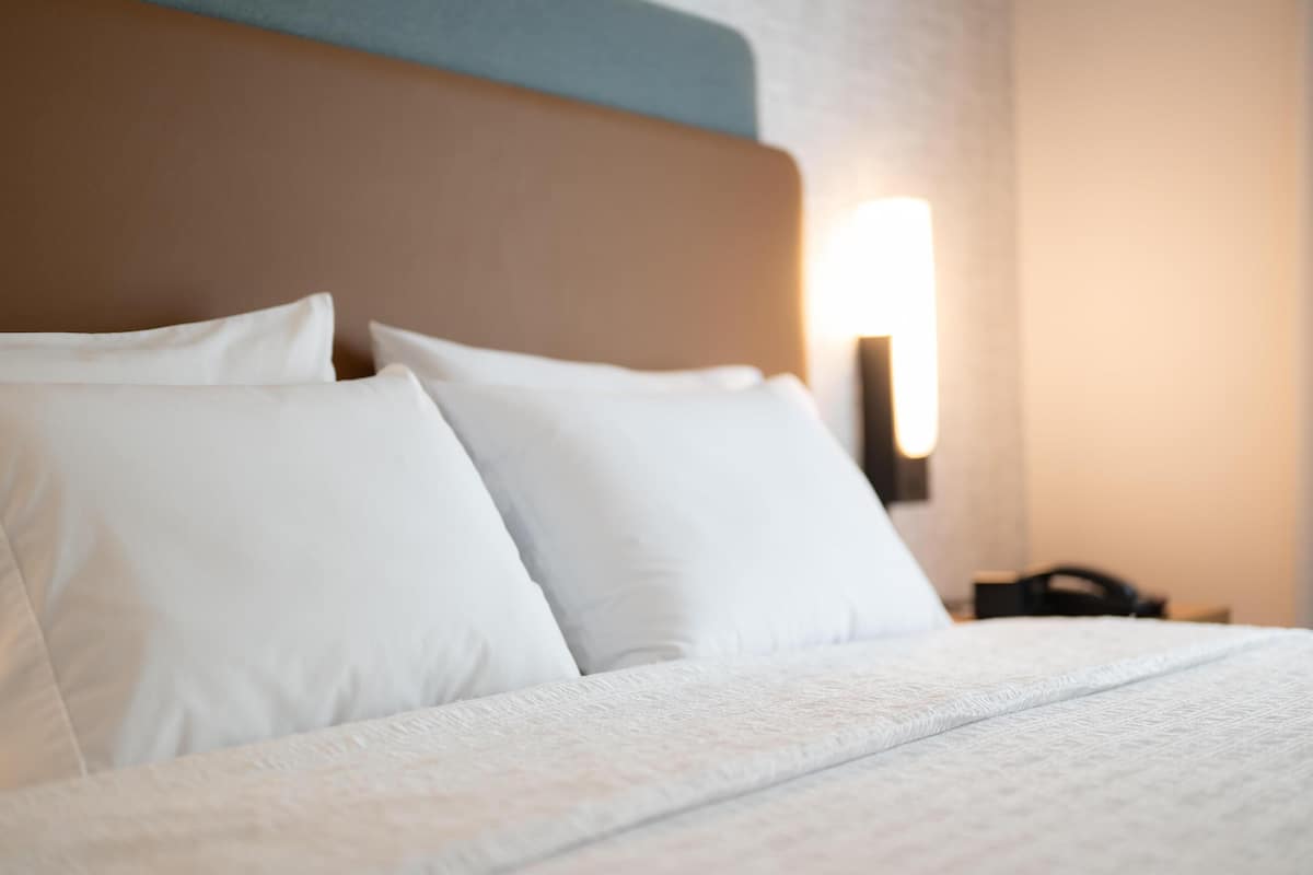 A neatly made bed with white linens and a headboard.