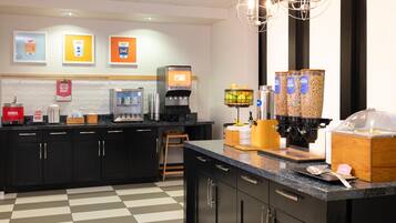 A modern kitchen with a coffee machine, cereal dispensers, and a sign for special dietary needs.