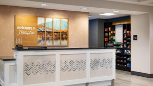 A reception area with a 'Welcome to Hampton' sign, a framed picture of a bridge, and a snack shop named 'Hilton Honors'. - Hampton Inn & Suites La Crosse Downtown (La Crosse)