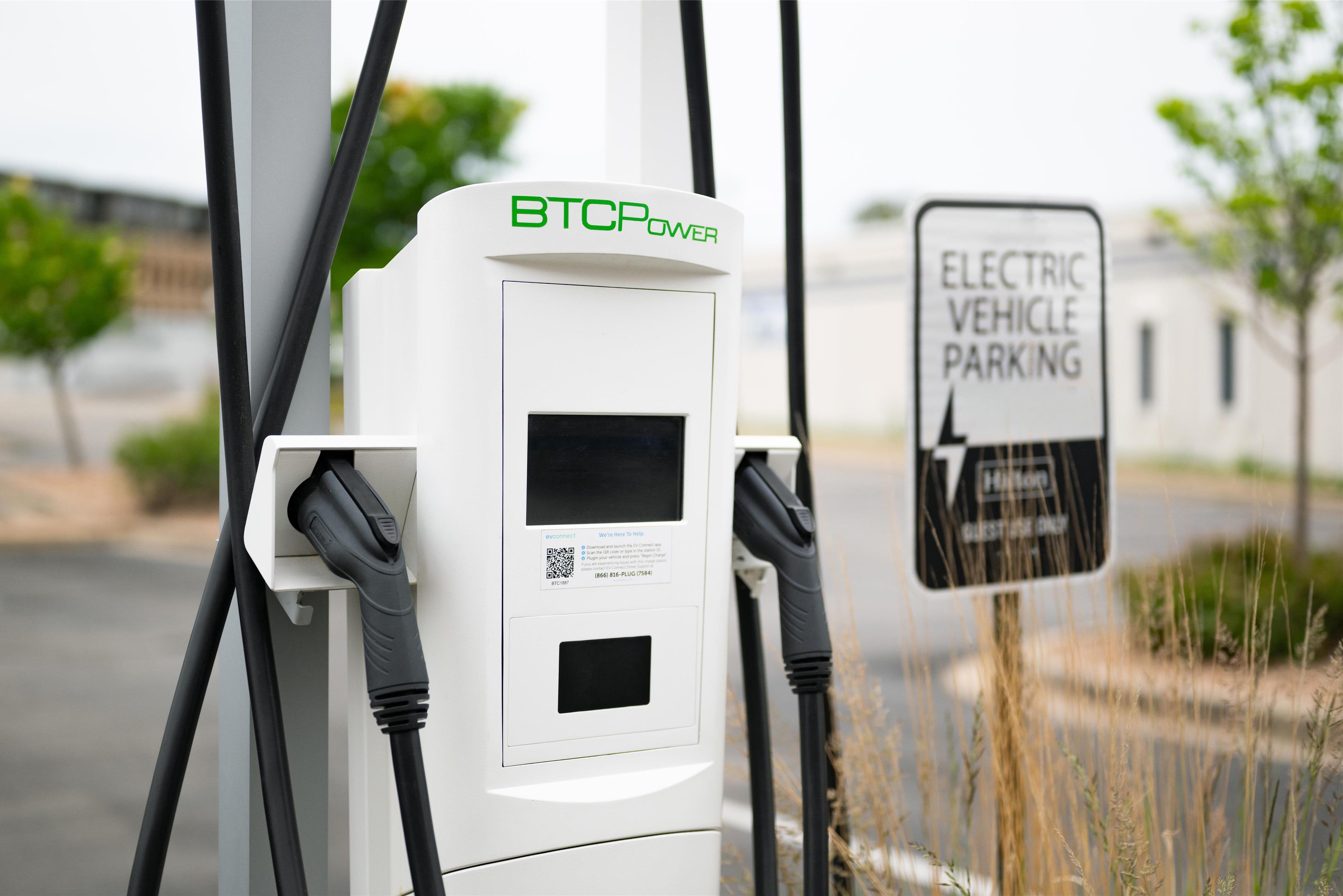 Estación de carga para vehículos eléctricos, con señalización indicando estacionamiento reservado para vehículos eléctricos.