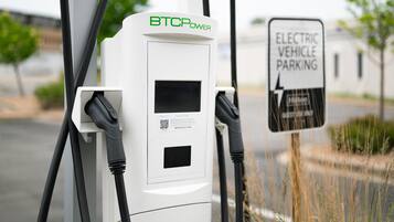 Estación de carga para vehículos eléctricos, con señalización indicando estacionamiento reservado para vehículos eléctricos.