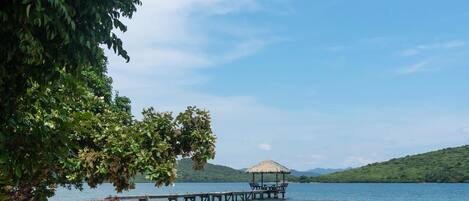 A beach with kayaks, lounge chairs, and a pier extending into the water.