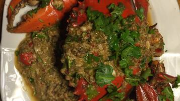A plate of cooked crab with a green herb sauce.
