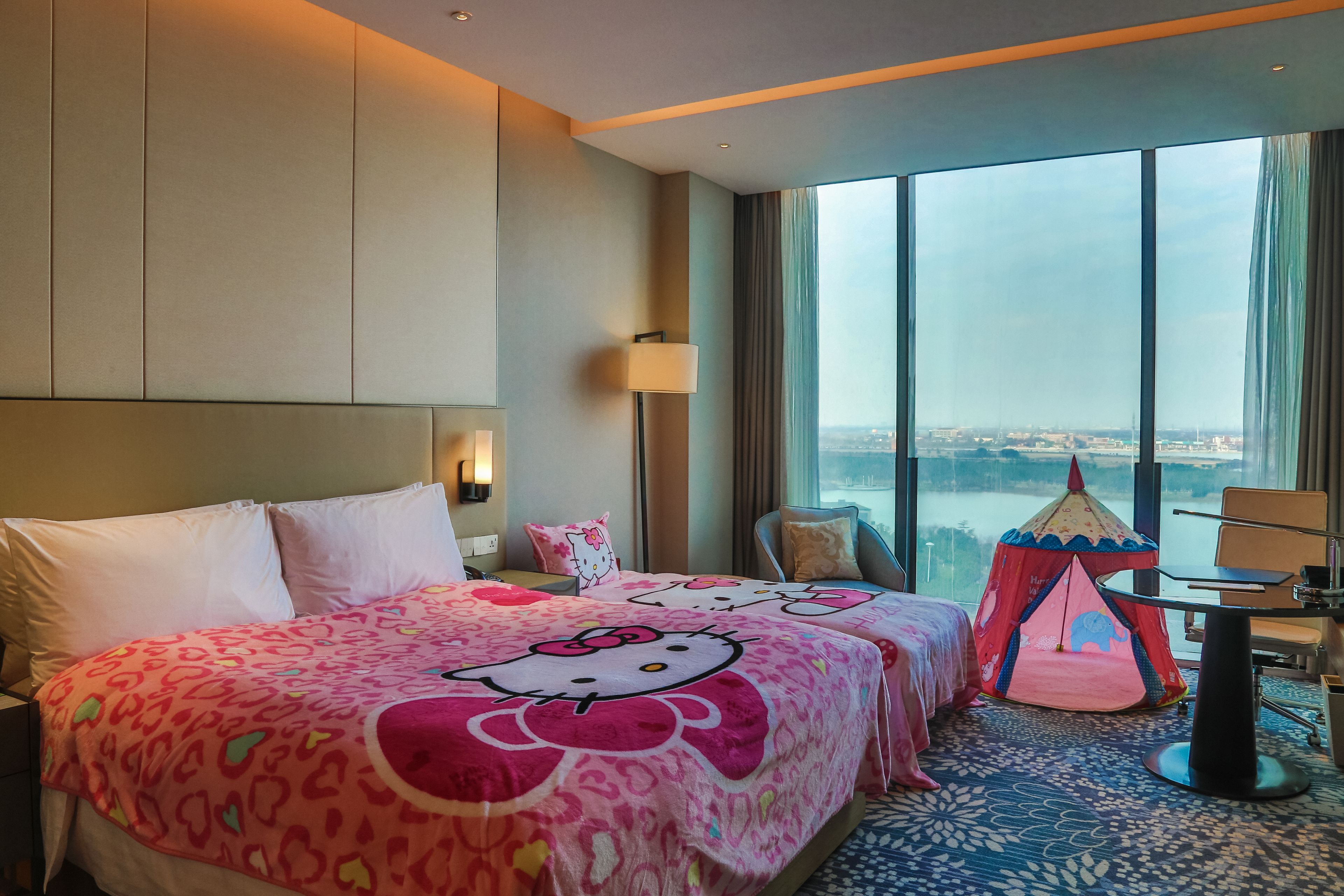 Una habitación de hotel con una cama grande, una tienda temática de Hello Kitty y vistas de la ciudad.