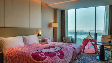 Una habitación de hotel con una cama grande, una tienda temática de Hello Kitty y vistas de la ciudad.