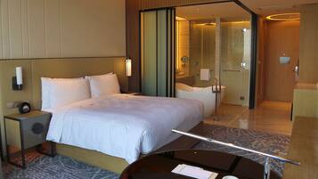 A hotel room with a bed, bedside table, and a desk with a chair.