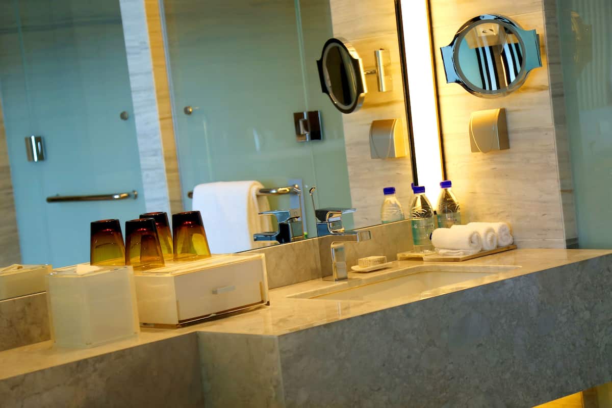 A modern bathroom with a marble sink, a large mirror, and a towel rack.