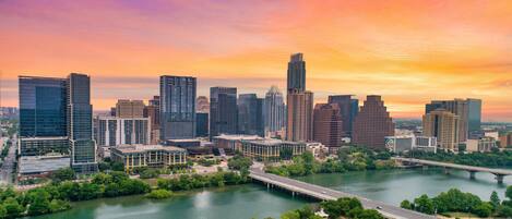 A city skyline with modern buildings, a river, and a bridge.