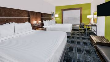 A hotel room with two beds, a desk, a chair, a TV, and a large window.