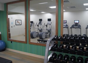 A gym with exercise equipment, a mirror, and a rack of dumbbells. - Holiday Inn Express & Suites Austin - Round Rock Area by IHG (Austin)
