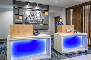 A reception desk with a digital screen, a wooden counter, and a sign for Holiday Inn Express & Suites.