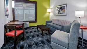 A room with a dining table, chairs, a sofa, and a patterned carpet.