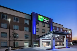 Een Holiday Inn Express & Suites hotel met een moderne gevel, grote ramen en een overdekt entreegebied.