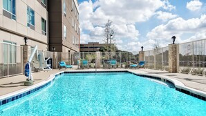 Une piscine avec des chaises longues et un mur en pierre.