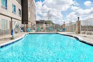A swimming pool with lounge chairs and a stone wall. - Holiday Inn Express & Suites Austin - Round Rock Area by IHG (Austin)