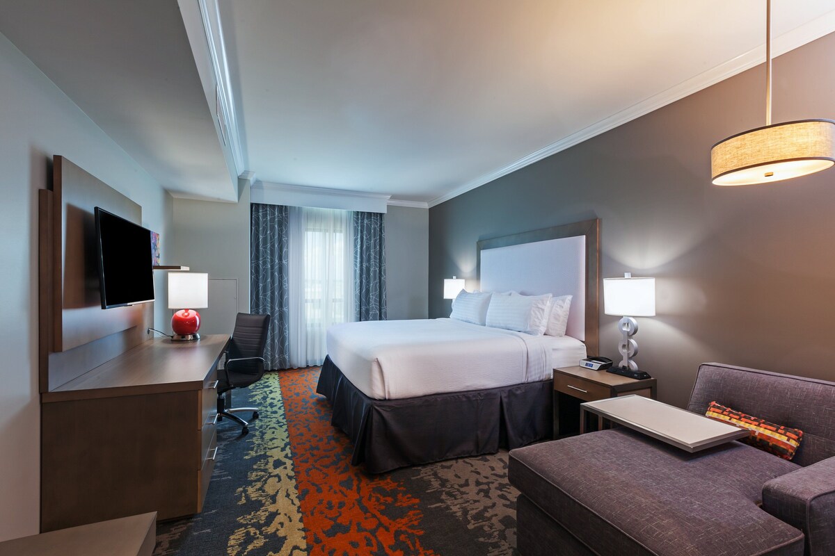 A hotel room with a bed, desk, chair, and a sofa.