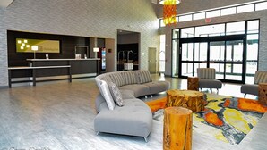 A modern lobby with a reception desk, a sectional sofa, and a colorful rug. - Holiday Inn Houston NE - Bush Airport Area by IHG (Humble)