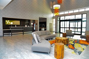 Un moderno vestíbulo con una recepción, un sofá modular y una alfombra colorida.