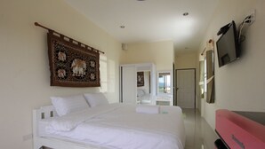 Una habitación de hotel con una cama grande, un televisor de pantalla plana montado en la pared y un armario rojo.