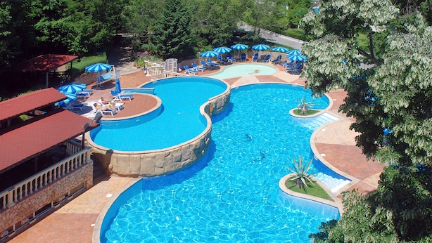 Una gran piscina de varios niveles con diferentes zonas de estar y sombrillas.
