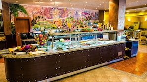 Un bufé con diversos platos, un mural en la pared y un ambiente tropical.