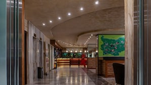 Un vestíbulo de hotel con piso de mármol, un mostrador de recepción y un gran mapa en la pared.