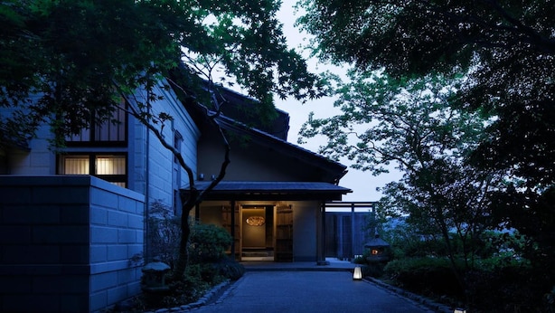 Une maison traditionnelle japonaise, avec une façade en bois, un toit recouvert de tuiles et un jardin bien entretenu.