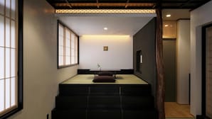 Une pièce de style japonais traditionnel, avec un sol recouvert de tatamis, une table basse avec des coussins et des portes coulissantes.