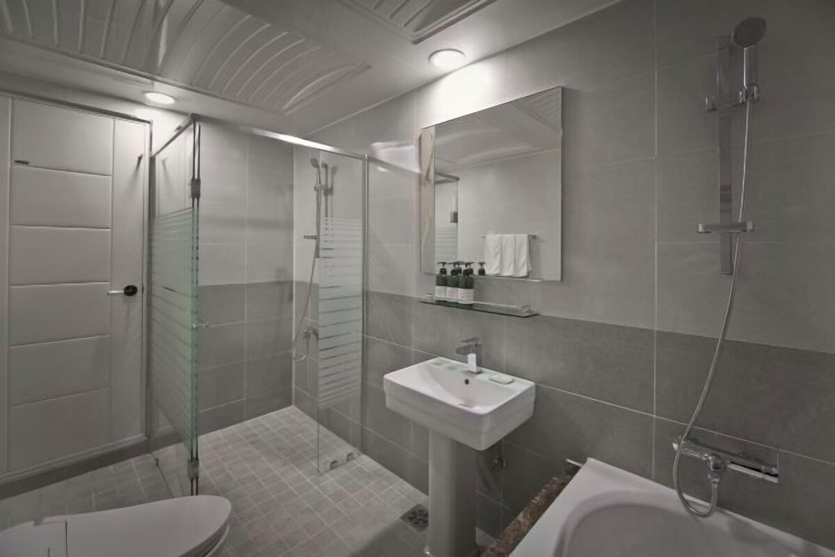 A modern bathroom with a glass-enclosed shower, a white sink, and a large mirror.