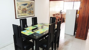 A dining area with a glass table, black chairs, and a framed picture on the wall. - Casa Vacacional Manatwar 2 (San Andrés)