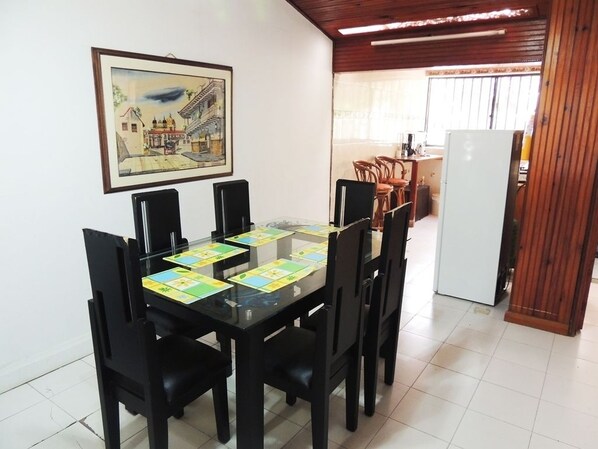 A dining area with a glass table, black chairs, and a framed picture on the wall.