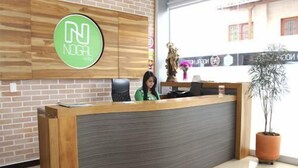 A reception desk with a logo, a statue, and a potted plant. - Nogal Hotel (La Ceja)