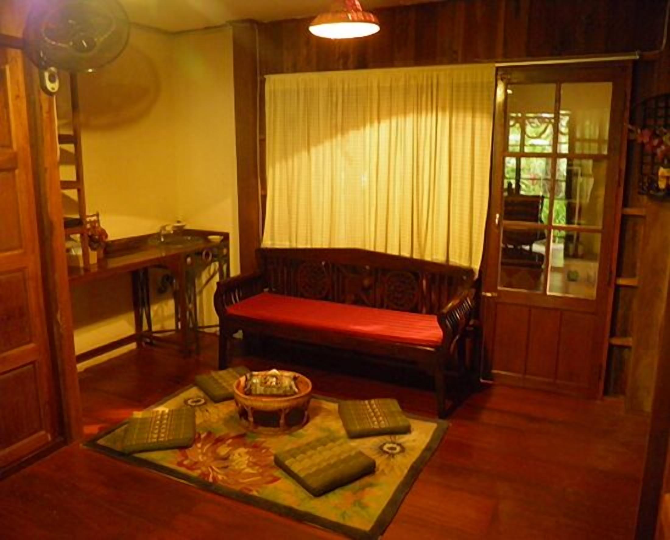 A traditional room with a wooden bench, a small table with a bowl, and a window with curtains.