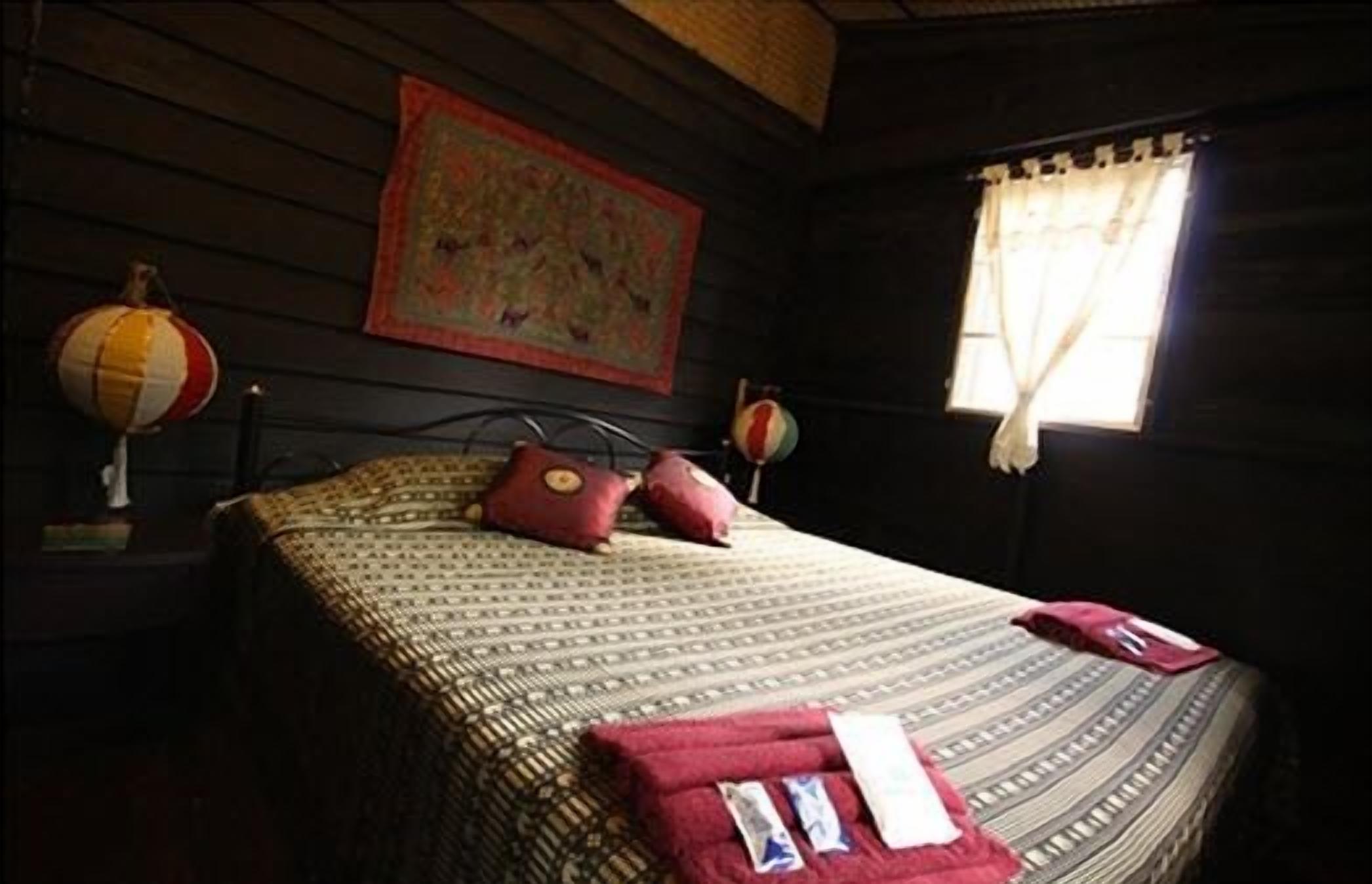 A cozy room with a bed, a painting on the wall, and a window with curtains.