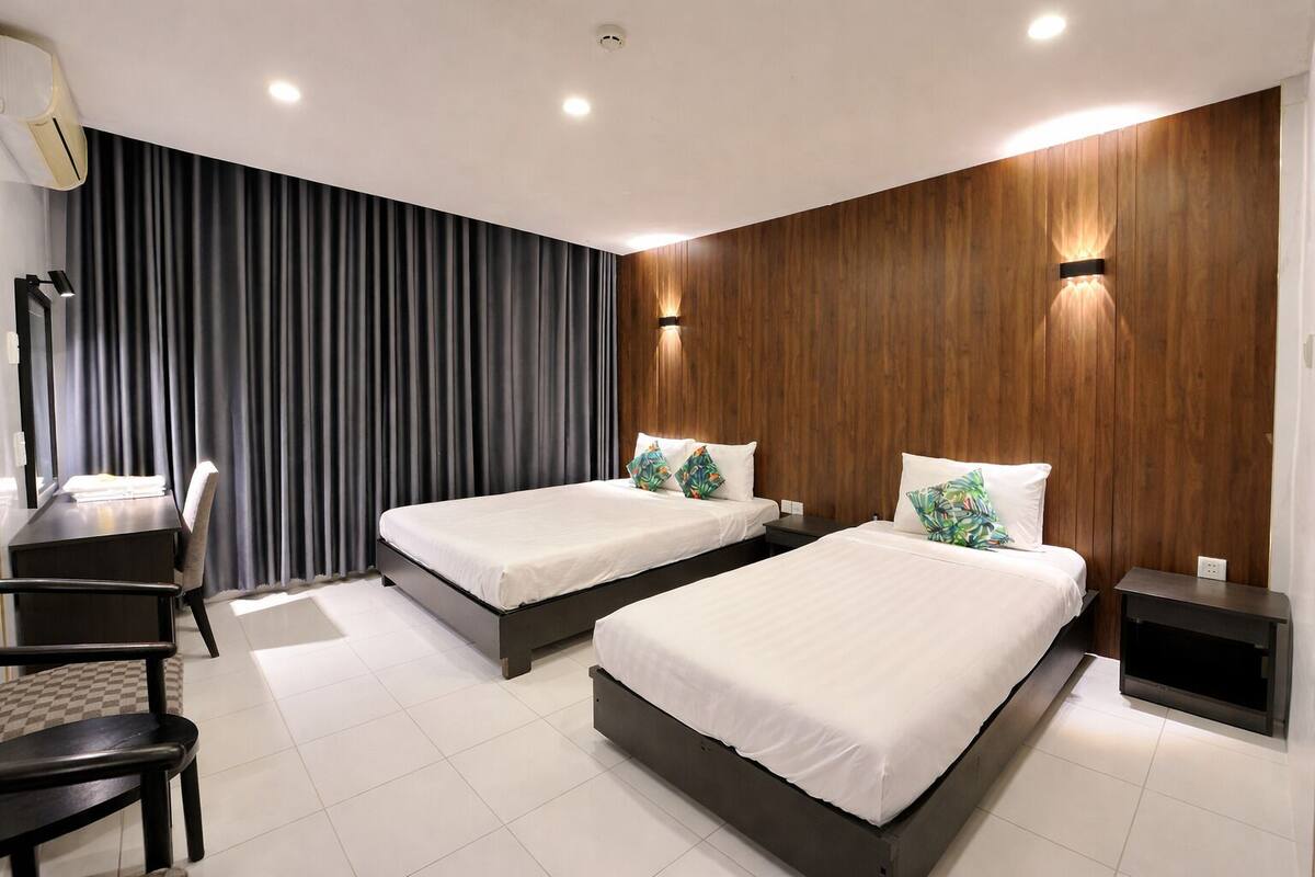 Une chambre d’hôtel moderne avec deux lits, un bureau et une chaise.
