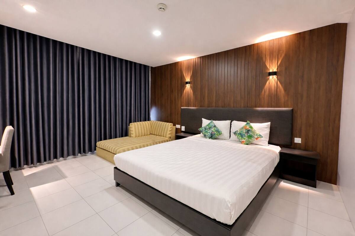 Une chambre d’hôtel moderne avec un grand lit, un canapé, un mur décoratif en bois et un rideau.