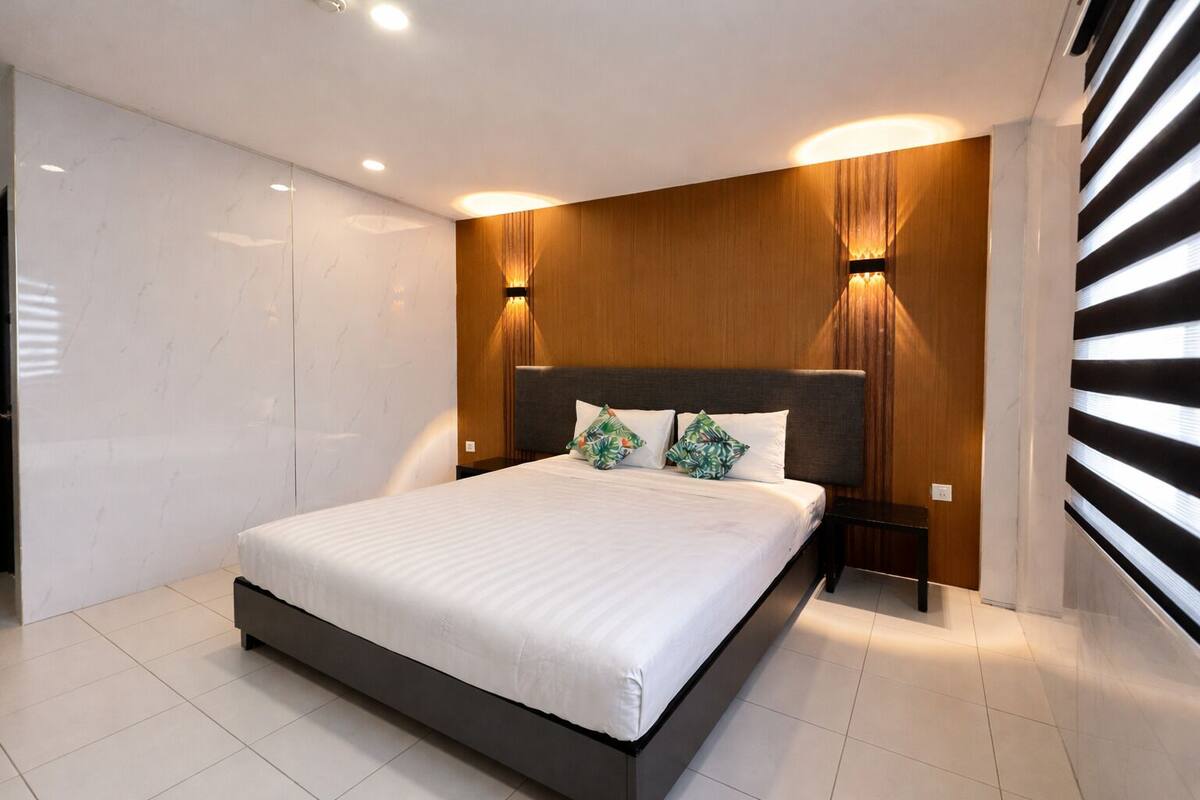 Une chambre moderne avec un grand lit, un mur revêtu de panneaux en bois et deux lampes fixées au mur.