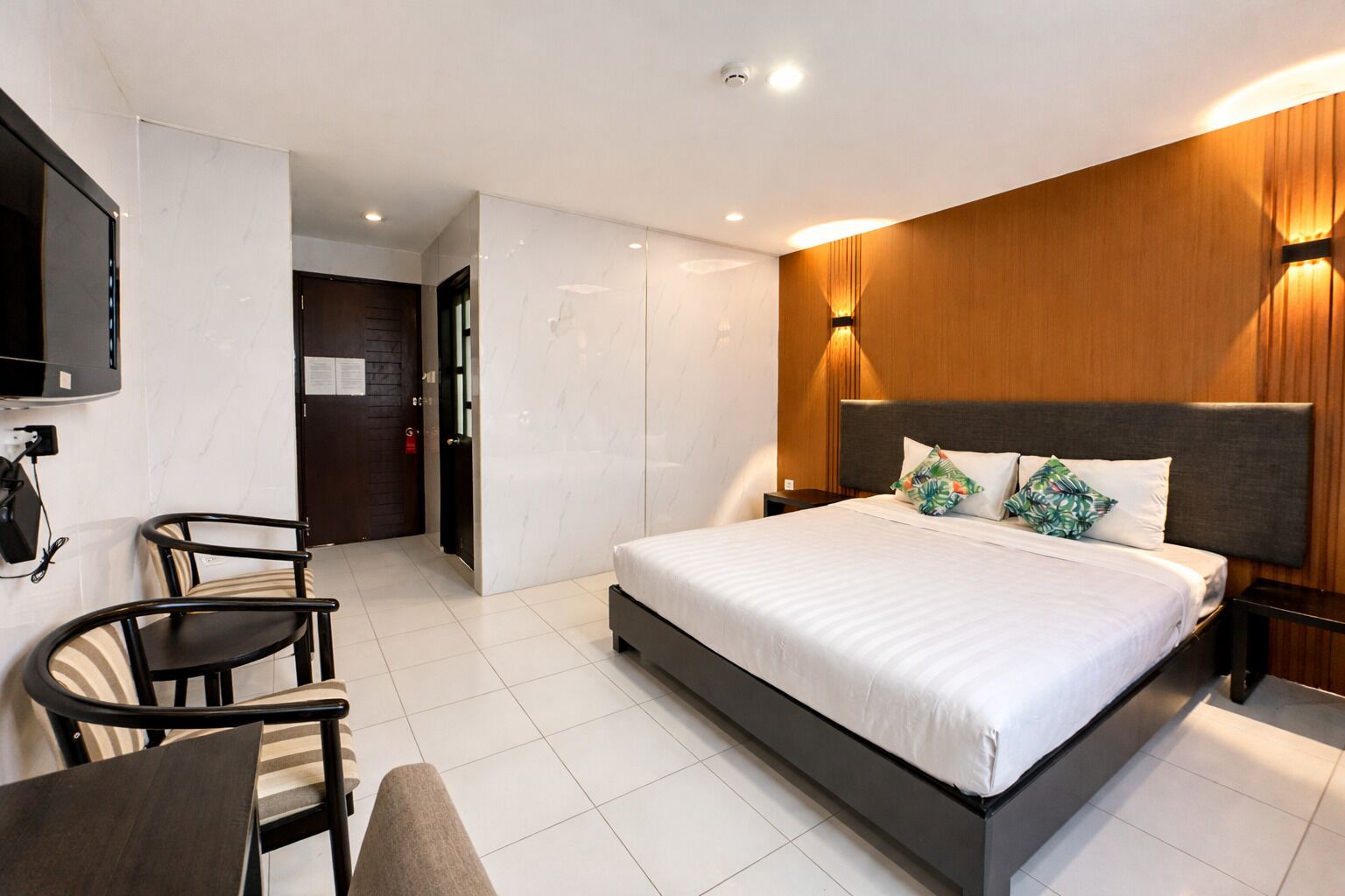 A modern hotel room with a large bed, a desk, and a TV.