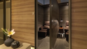 Quarto moderno com piso de madeira, um sofá, uma mesa pequena e uma luminária.
