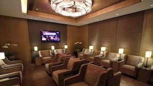 Sala de massagem com várias cadeiras de massagem, uma televisão na parede e iluminação ambiente.