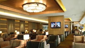 Um hall de hotel com fileiras de assentos, um grande candelabro e várias televisões nas paredes.