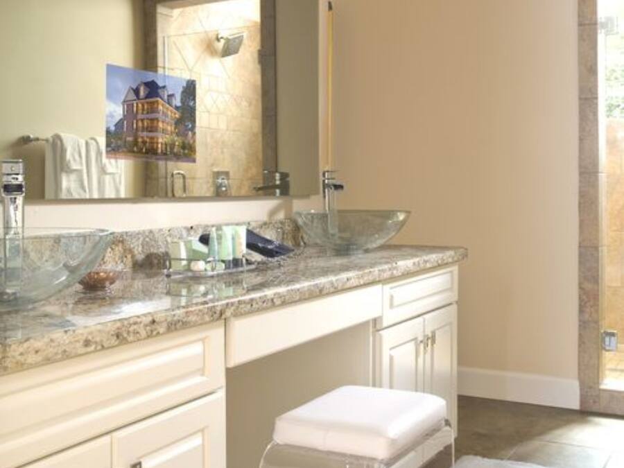 Un baño con un espejo grande, un lavabo de vidrio y un tocador blanco.
