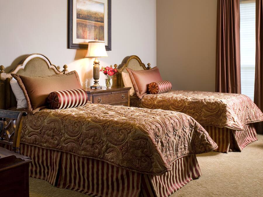 Une chambre d’hôtel avec deux lits, une table de chevet, une lampe et un tableau encadré au mur.