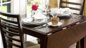 Mesa para dos personas dispuesta con un florero, platos y cubiertos.