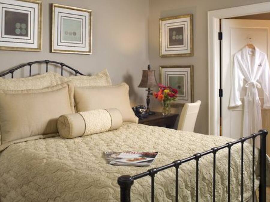 A neatly made bed with a quilted cover, a bedside table with a lamp, and a framed picture on the wall.