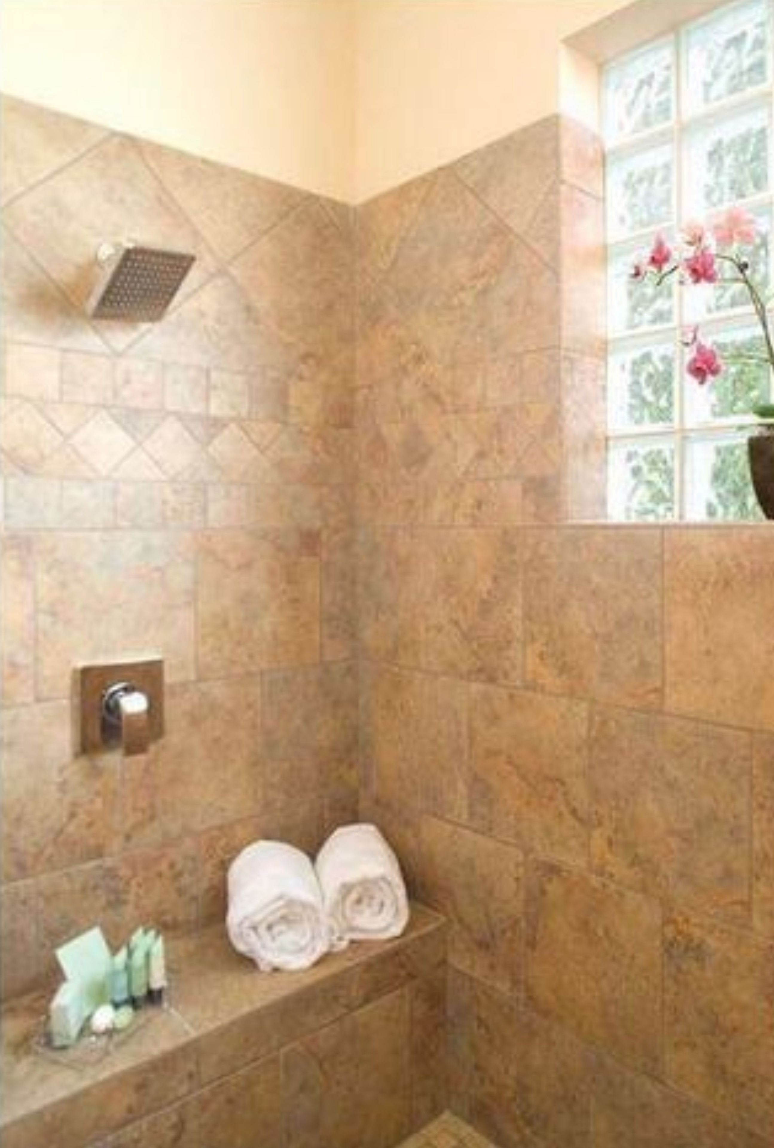 A bathroom with a shower, a window with a view, and towels on a bench.