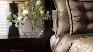 Un dormitorio con una cama, una mesita de noche, una lámpara y un florero con flores.